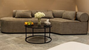 A modern room with a sofa, a round table with a vase and fruits, and a neatly made bed. - Salmiya Grand Hotel (Salmiya)