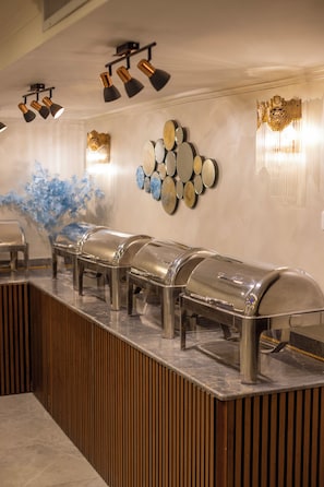 A buffet area with multiple self-service stations, wall-mounted mirrors, and decorative wall sconces. - Salmiya Grand Hotel (Salmiya)
