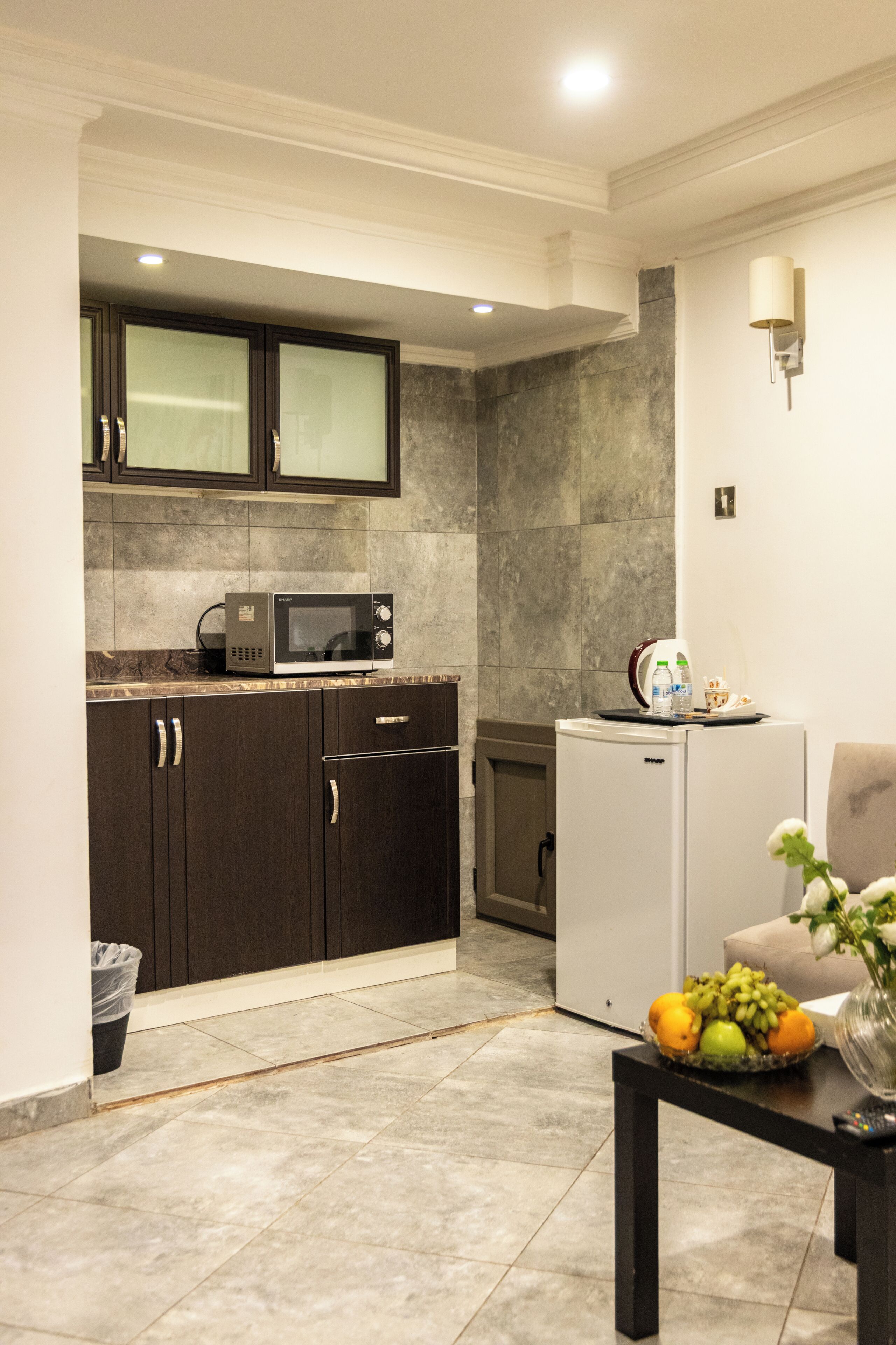A compact kitchen with a microwave, refrigerator, and a dining area with a table set for two.