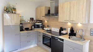 A modern kitchen with wooden cabinets, stainless steel appliances, and a built-in dishwasher. - 5 Sterne Fewo-Pausendomizil' with Private Terrace, Private Garden and Wi-Fi (Ebstorf)