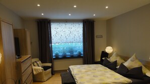 A bedroom with a bed, bedside table, lamp, curtains, window, and a television. - 5 Sterne Fewo-Pausendomizil' with Private Terrace, Private Garden and Wi-Fi (Ebstorf)