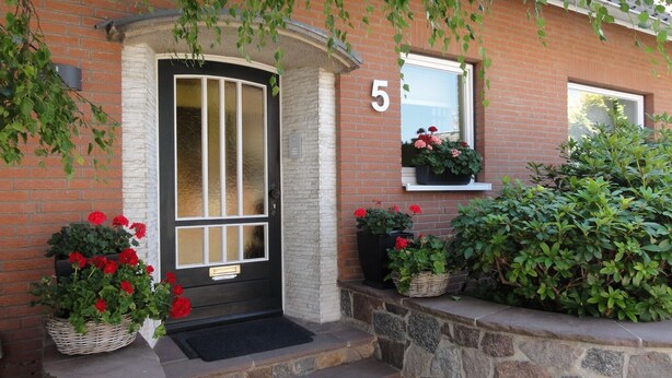 A brick house with a black door, number 5, potted plants, and a window with flowers. - 5 Sterne Fewo-Pausendomizil' with Private Terrace, Private Garden and Wi-Fi (Ebstorf)