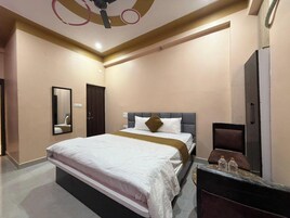 Habitación de hotel con una cama grande, un armario, un espejo y un ventilador de techo.