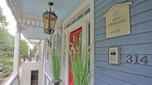 A porch with a red door, a lamp, and a sign indicating the house number 314. - Charming Historic Apt Steps to River St & Tours (Savannah)