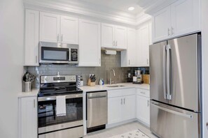 A modern kitchen with white cabinets, stainless steel appliances, and a tiled backsplash.