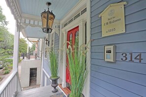 A porch with a red door, a lamp, and a sign indicating the house number 314.