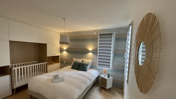 Un dormitorio moderno con cama, mesita de noche y espacio de almacenamiento integrado.