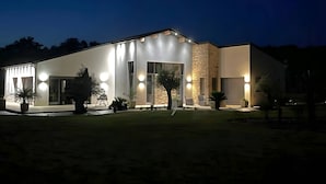 Una casa moderna con exterior bien iluminado, ventanas amplias y un muro de acento de piedra.