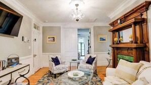 A living room with a fireplace, two armchairs, a sofa, a glass coffee table, and a television.