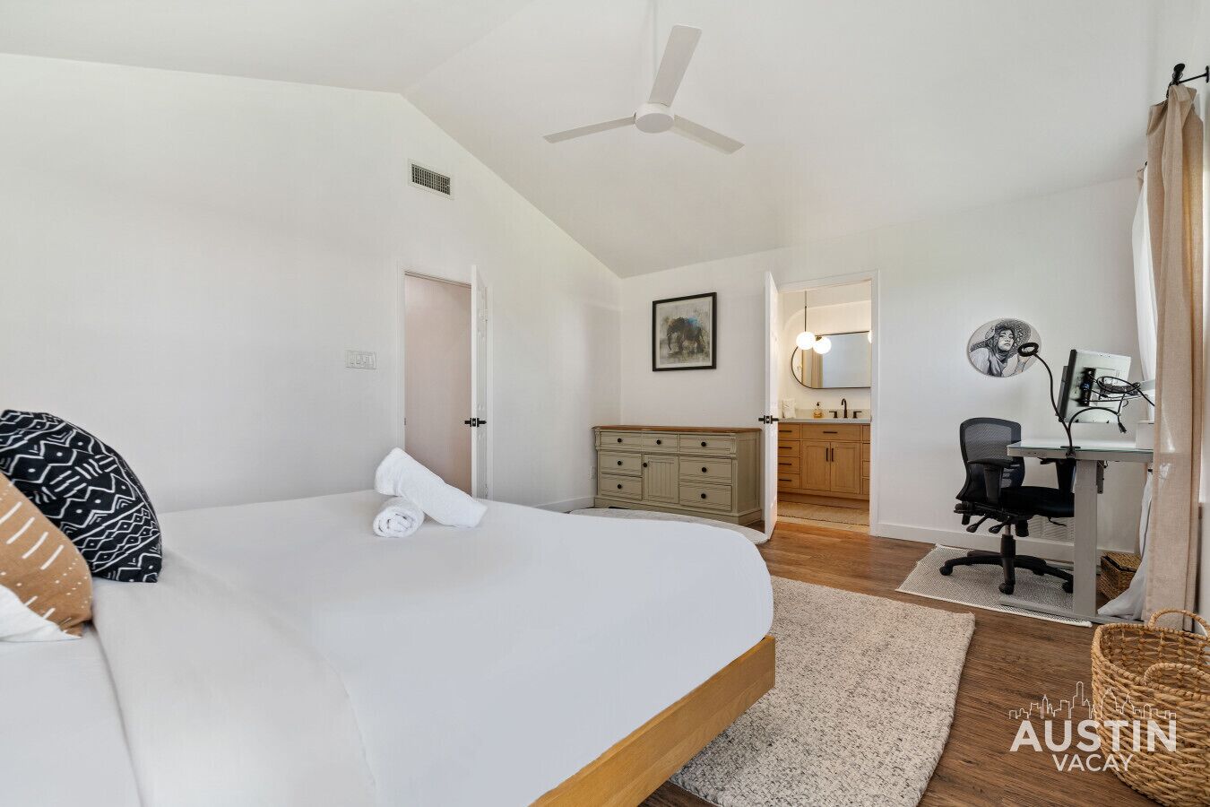 Una camera da letto con un letto, una scrivania, una sedia, un comò e una ventola a soffitto.