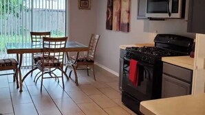 Una cocina equipada con estufa, microondas y comedor con sillas y mesa.