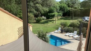 A view of a swimming pool with lounge chairs and umbrellas, surrounded by a garden and trees. - Villa in France With Private Pool & Garden (Prades-sur-Vernazobre)