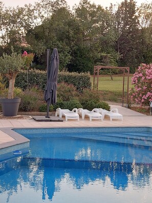 A swimming pool with lounge chairs and a pergola in a landscaped garden. - Villa in France With Private Pool & Garden (Prades-sur-Vernazobre)