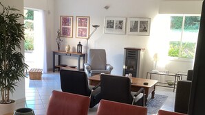 A spacious living room with a wooden dining table, several chairs, a fireplace, and framed pictures on the wall. - Villa in France With Private Pool & Garden (Prades-sur-Vernazobre)