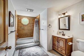 Une salle de bain avec une cabine de douche en bois, un lavabo blanc avec un meuble-lavabo en bois, et un grand miroir au-dessus du lavabo.
