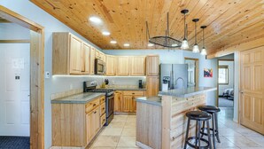 Una cocina con armarios de madera, una isla central con taburetes, un microondas y un refrigerador.