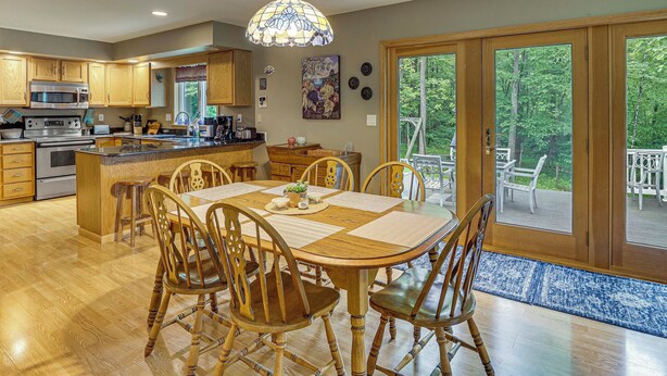 A spacious kitchen with wooden cabinets, a large island, and a dining area with a wooden table and chairs. - 2 Mi to Woodbury Wildlife Area: Cozy Farmhouse! (Warsaw)