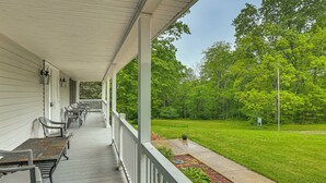 A covered porch with outdoor seating, a grassy yard, and trees in the background. - 2 Mi to Woodbury Wildlife Area: Cozy Farmhouse! (Warsaw)
