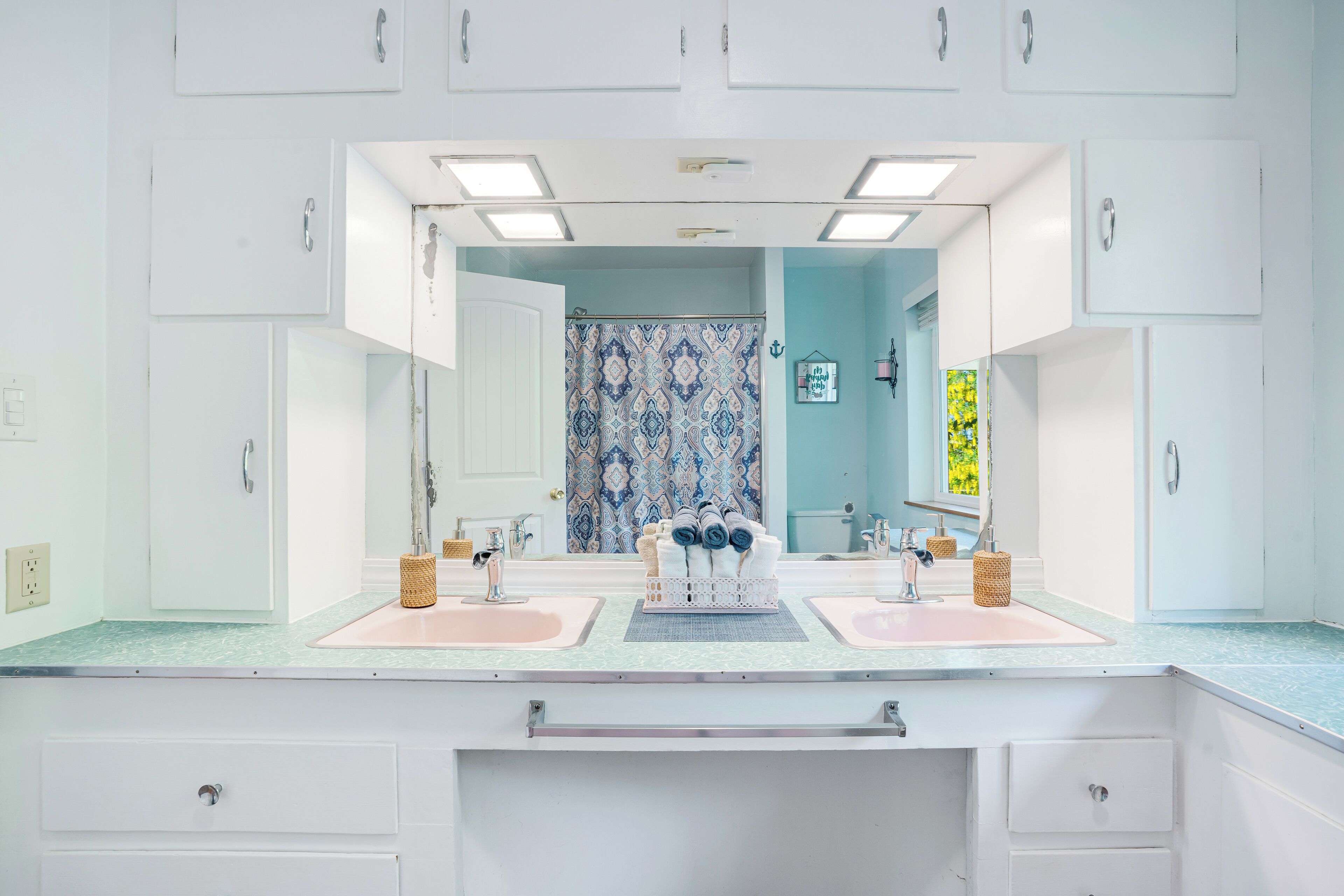 A bathroom with two sinks, a large mirror, and a patterned shower curtain.