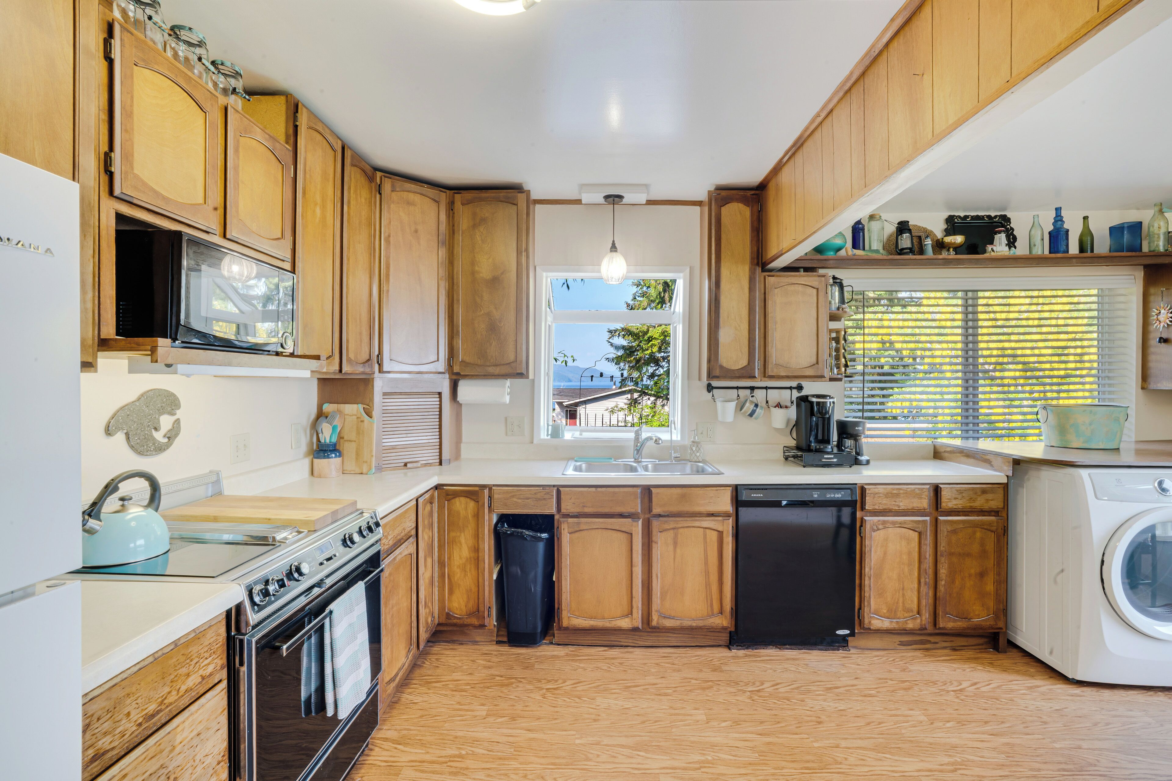 A compact kitchen with wooden cabinets, a microwave, a stove, a dishwasher, and a sink.