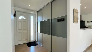 A hallway with a sliding door, a black mat at the entrance, and a wall-mounted light fixture.