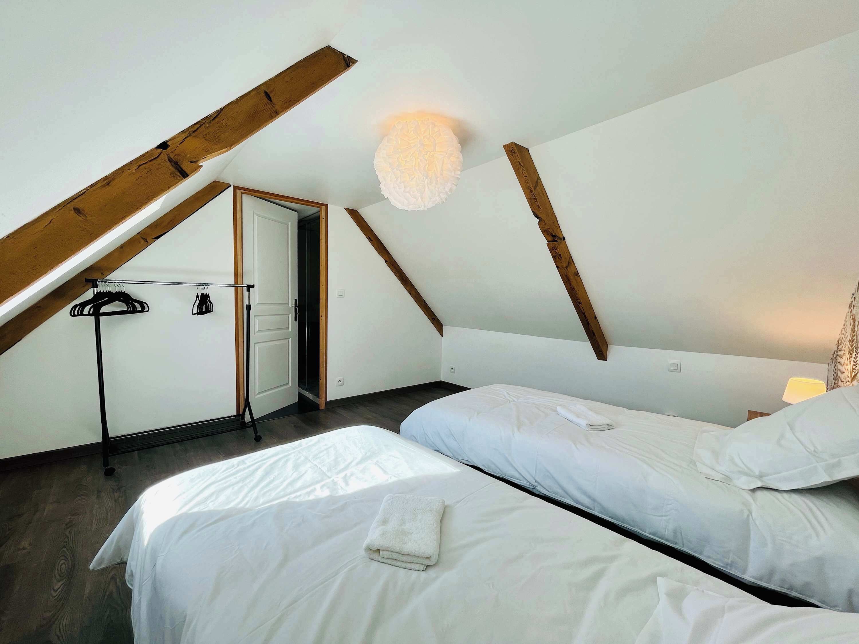 Een slaapkamer met twee bedden, een plafondventilator en een deur naar een andere kamer.