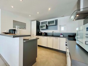 A modern kitchen with a central island, built-in appliances, and a sleek design. - Gîte de la Fontaine - Family house in Carentan (Carentan-les-Marais)