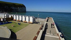 A coastal area with a row of white beach huts, a grassy area with benches, and a view of the sea and cliffs. - Elegant Chateau Escape for 2 - Nature & Calm (Nointot)