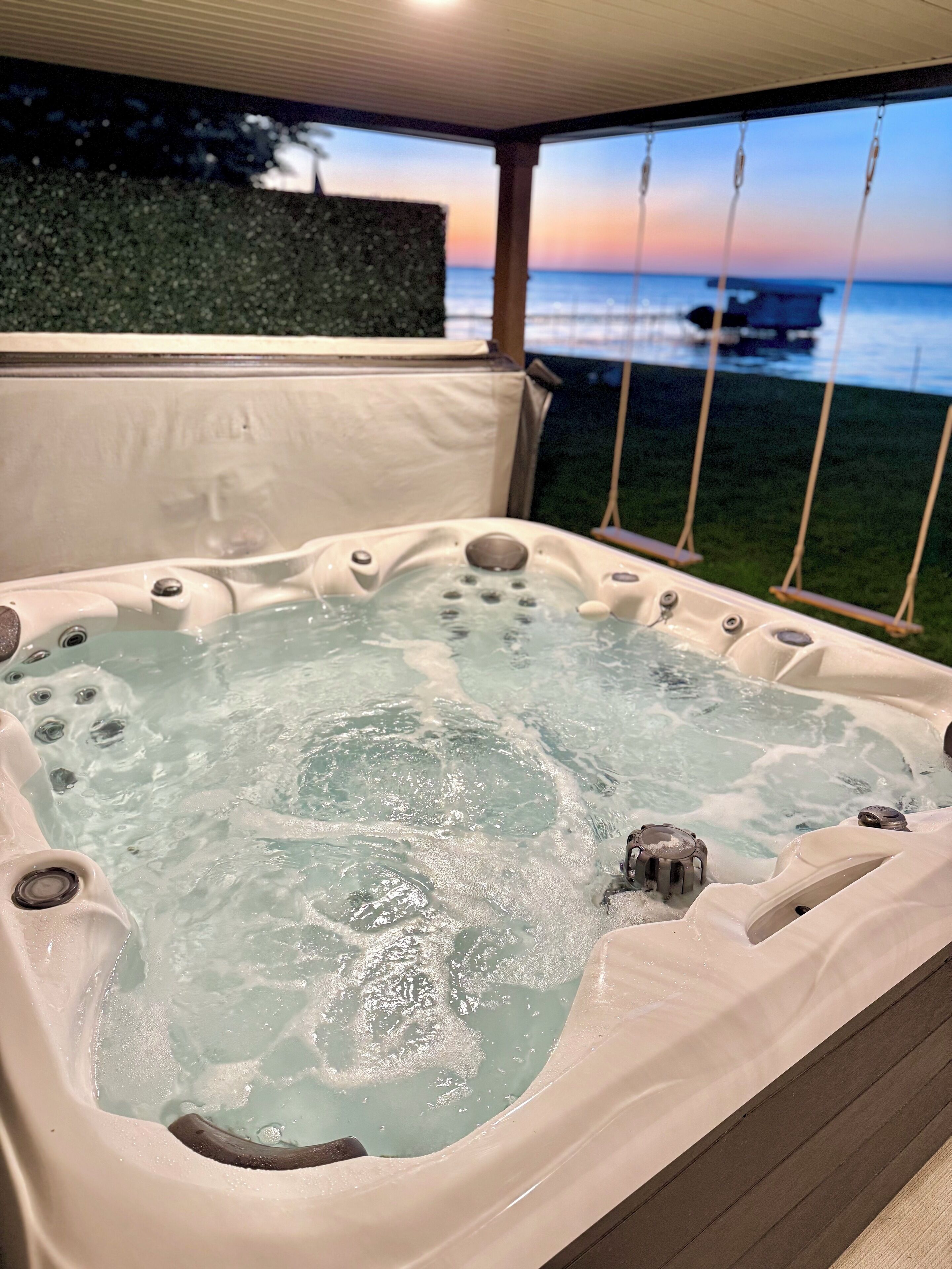 A hot tub with a view of the ocean at sunset.