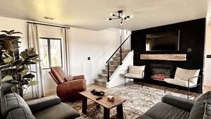 A modern living room with a large sectional sofa, a coffee table, and a fireplace.