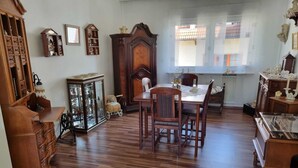 Une salle à manger spacieuse, avec une table et des chaises en bois, entourée de meubles anciens et d’une grande armoire.