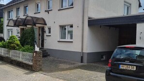 Une maison à deux étages, avec un toit en tuiles, une allée couverte et une voiture garée.