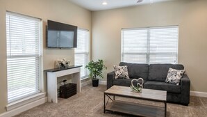 A living room with a sofa, coffee table, TV, fireplace, and large windows.
