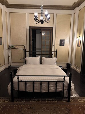 A bed with a metal frame, a chandelier, a wooden door, and a wall-mounted picture frame. - Spacious 5-bedroom apartment with AC, WiFi in fantastic Cairo Governorate (Cairo Governorate)