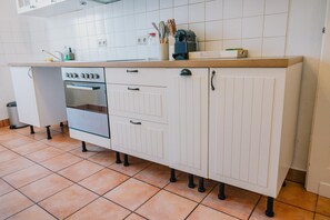 A kitchen with white cabinets, a built-in oven, and a countertop with kitchen utensils.