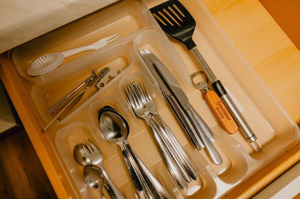 A drawer containing various utensils including forks, spoons, a knife, and a spatula.