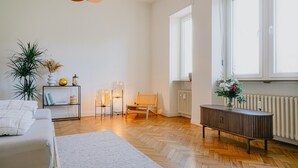 Ett modernt vardagsrum med en soffa, ett trägolv, ett vitt element och ett fönster med persienner.