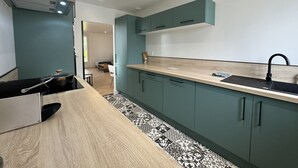 A modern kitchen with teal cabinets, a wooden countertop, and a black sink. - Peaceful Home With Terrace & Parking (Le Mans)