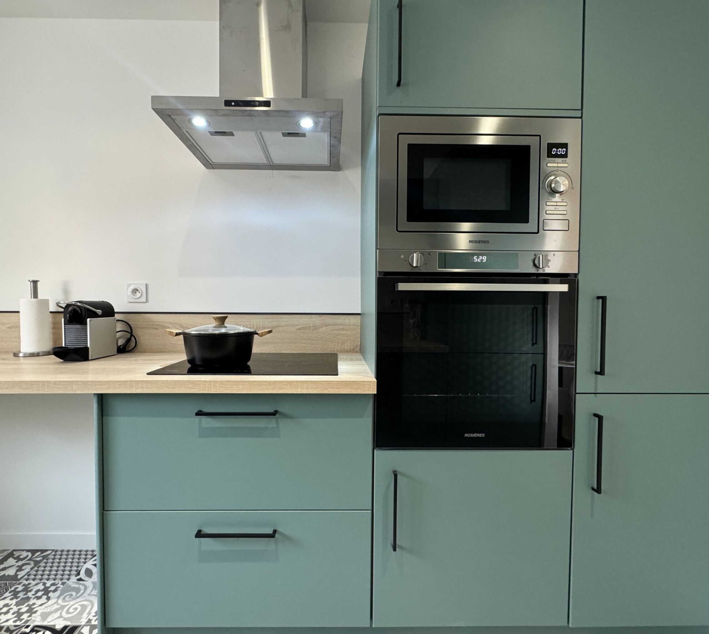 A kitchen with a microwave, oven, and a pot on the counter.