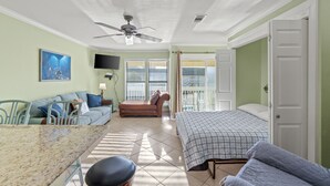 Ein Zimmer mit einem Bett, einem Sofa, einem Esstisch und einem Deckenventilator.