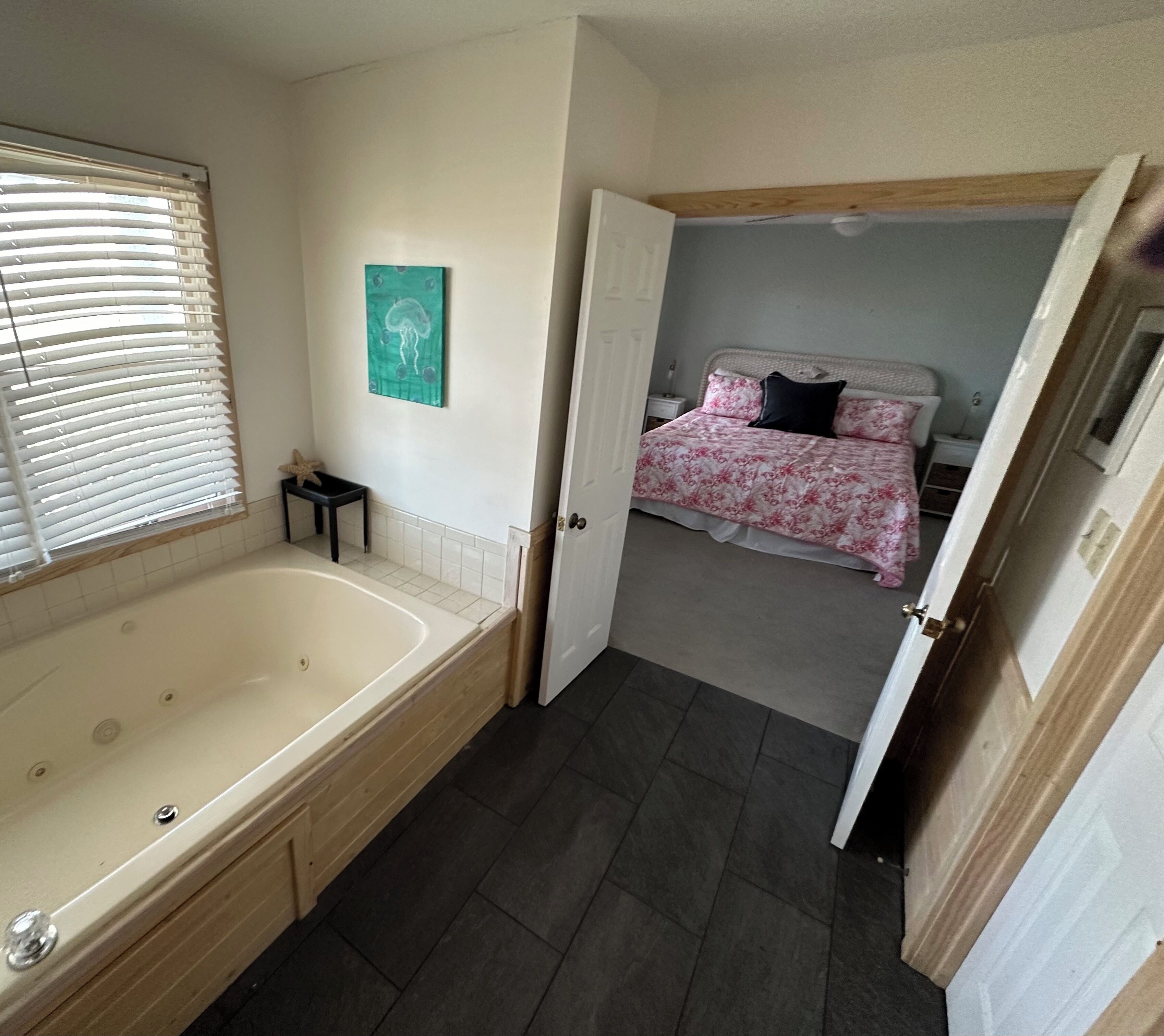 A bathroom with a bathtub, a small table with a starfish decoration, and a wall-mounted artwork.