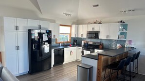A modern kitchen with white cabinets, a black refrigerator, a stainless steel range, and a wooden island with bar stools. - Welcome to Wreckless! Beautiful home with AC and WIFI in delightful Avon (Avon)