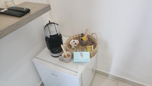 Une petite cuisine équipée d’une machine à café, d’un panier rempli d’en-cas et d’un service à thé.