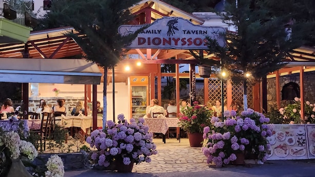 Une taverne familiale avec une terrasse et une façade en pierre.