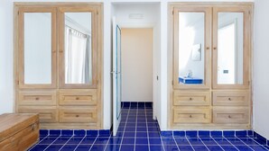 A hallway with wooden doors, a blue tiled floor, and a wooden bench.