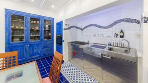 A kitchen with blue cabinets, a stainless steel sink, and a tiled backsplash.