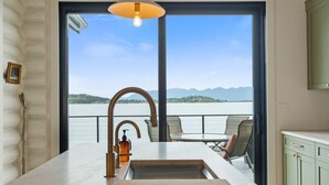 Eine Küche mit einem großen Fenster, Blick auf einen See und einer Essecke mit Stühlen.