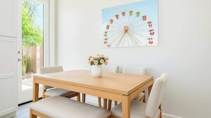 A dining area with a wooden table and four chairs, a vase with flowers, and a wall-mounted picture of a Ferris wheel. - Cozy 2BR Getaway, 3 Bd/2BA (Glendale)