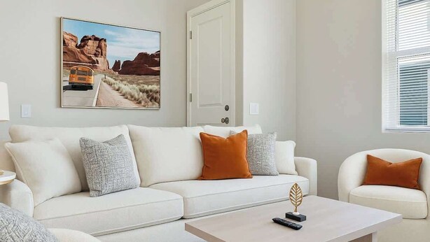 A modern living room with a white sofa, a coffee table, and a painting of a desert landscape. - Cozy 2BR Getaway, 3 Bd/2BA (Glendale)