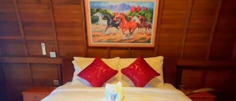 A wooden-paneled room with a bed, red and white bedding, and a painting of horses on the wall.